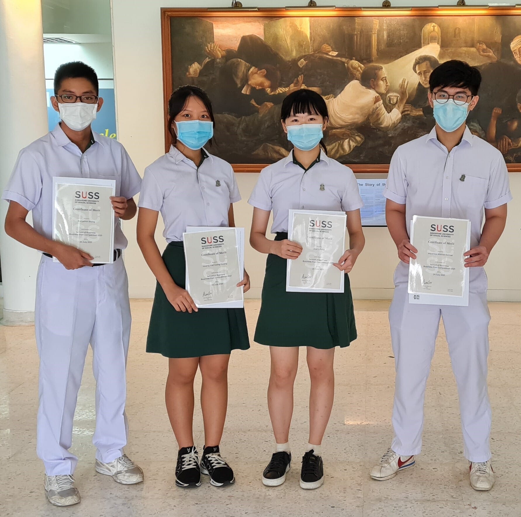 Four masked students hold SUSS Certificate of Merit awards for the School of Business Plan Competition 2021, before a large mural.